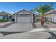 Charming single-story home with a well-maintained yard, a palm tree, and a two-car garage at 1060 Neil Armstrong Cir, Las Vegas, NV 89145