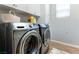 This laundry room features a side-by-side washer and dryer, storage cabinets, and sleek wood-look tile flooring at 10750 Red Badge Ave, Las Vegas, NV 89166