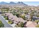 An aerial view captures a neighborhood with pools, lush trees, and beautiful mountain views at 11112 Pine Greens Ct, Las Vegas, NV 89144