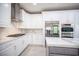 A kitchen featuring white cabinets, stainless steel appliances, a modern hood, and marble countertops at 11112 Pine Greens Ct, Las Vegas, NV 89144