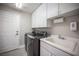 Functional laundry room with a sink, white cabinets, and modern washer and dryer at 11112 Pine Greens Ct, Las Vegas, NV 89144