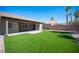 A well-maintained backyard with artificial turf, a covered patio, and a brick wall, perfect for relaxation at 11119 River Hills Ln, Las Vegas, NV 89135