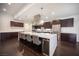 Contemporary kitchen with a large quartz island with seating, pendant lights, and dark wood cabinets at 11119 River Hills Ln, Las Vegas, NV 89135