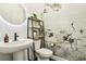 Chic powder room features a pedestal sink, floral wallpaper, and a modern round mirror at 12155 Sage Thunder Ave, Las Vegas, NV 89138