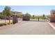 Neighborhood entry gate with stone pillars, metal gate, street signage, and distant mountain views at 12155 Sage Thunder Ave, Las Vegas, NV 89138
