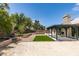 Large backyard with artificial turf, desert landscaping, patio cover, and mature trees at 1673 Golden Vista Dr, Las Vegas, NV 89123