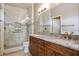 Bright bathroom featuring a double sink vanity with granite countertop and glass enclosed shower with marble tile surround at 1782 Black Fox Canyon Rd, Henderson, NV 89052