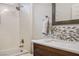 Well lit bathroom with a shower/tub combo, and wood vanity with a white countertop and decorative backsplash at 1782 Black Fox Canyon Rd, Henderson, NV 89052