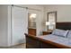 Comfortable bedroom with a slider leading to the bathroom, a stylish mirror and a nightstand with lamps at 1782 Black Fox Canyon Rd, Henderson, NV 89052
