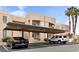 Beige condo building featuring covered parking, landscaped grounds, and palm trees at 2232 Aspen Mirror Way # 202, Laughlin, NV 89029