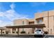 Beige condo building featuring covered parking, landscaped grounds, and clear blue sky at 2232 Aspen Mirror Way # 202, Laughlin, NV 89029