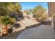 A concrete patio looks onto a xeriscaped backyard with mature trees and shrubbery at 3342 Pheasant Canyon Way # 1013, Laughlin, NV 89029