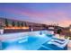 A stunning pool with a waterfall feature and an integrated hot tub is surrounded by lush greenery and lighting at 4505 Amazing View St, Las Vegas, NV 89129