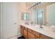 Well-lit bathroom with double sinks, wood cabinets, large mirror, and modern lighting fixtures at 4804 Laurentia Ave, Las Vegas, NV 89141