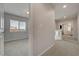 Hallway view showing neutral colored walls and carpet, with bedrooms and a window for natural light at 6056 Atlantis Dream Ave, Las Vegas, NV 89139