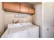 Well-lit laundry room with washer and dryer and ample cabinet space above appliances at 6408 Deadwood Rd, Las Vegas, NV 89108