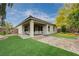A charming covered patio with an outdoor seating area overlooks the landscaped backyard and artificial turf at 7052 Blissful Peak St, North Las Vegas, NV 89084