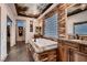 Lavish bathroom features a soaking tub with stone surround, unique ceiling mural, and stone accent wall at 7501 Midnight Rambler St, Las Vegas, NV 89149