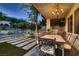 Outdoor dining area with decorative wrought iron chairs and a built-in grill next to the sparkling pool at 7501 Midnight Rambler St, Las Vegas, NV 89149