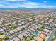 Wide aerial shot of closely arranged homes in a residential area with a school in the distance under clear blue skies at 7545 Fontera Ct, Las Vegas, NV 89139