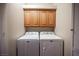 Bright laundry area with wood cabinets located above the washer and dryer at 7911 Canoe Ln, Las Vegas, NV 89145