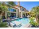 An inviting backyard area complete with a pool, patio seating, and lush palm trees at 7940 Castle Pines Ave, Las Vegas, NV 89113