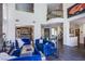 Open-concept living room with high ceilings, large windows, stylish blue sofas and access to the bar area at 7940 Castle Pines Ave, Las Vegas, NV 89113