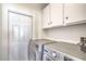 Practical laundry room features modern washer and dryer, white cabinets, and a white door at 7964 Lovely Pine Pl, Las Vegas, NV 89143