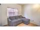 Cozy living space features neutral walls, tiled floors, and a comfortable gray couch at 7964 Lovely Pine Pl, Las Vegas, NV 89143