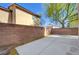 Enclosed backyard featuring a concrete patio, brick walls, and mature trees at 8396 Pearl Beach Ct, Las Vegas, NV 89139
