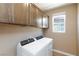 Laundry room with upper cabinets, a window, and a modern washer and dryer set at 8873 Howell St, Las Vegas, NV 89166