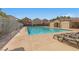 Community pool area featuring chaise lounges for relaxing, a gated perimeter, and nearby trees at 9174 Mcginnis Ave, Las Vegas, NV 89148