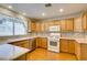 Bright kitchen featuring wooden cabinets, white appliances, tile backsplash, and a window over the sink at 10009 Netherton Dr, Las Vegas, NV 89134