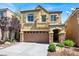 Two-story home featuring a two-car garage, stone accents, balcony, and landscaped front yard at 10230 Danskin Dr, Las Vegas, NV 89166