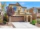 Two-story home featuring a two-car garage, stone accents, balcony, and landscaped front yard at 10230 Danskin Dr, Las Vegas, NV 89166
