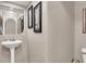 Neutral-toned powder room with pedestal sink, decorative mirror, and framed artwork at 10230 Danskin Dr, Las Vegas, NV 89166