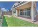 Backyard featuring a covered patio, artificial grass, and brick paver walkway at 10433 Smokey Mariposa Ave, Las Vegas, NV 89166