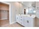 Bathroom featuring a dual sink vanity, large mirror, and walk-in closet access at 10433 Smokey Mariposa Ave, Las Vegas, NV 89166
