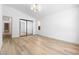 Bright bedroom featuring wood-look flooring, a modern light fixture, and a closet with mirrored doors at 10540 Beachwalk Pl, Las Vegas, NV 89144