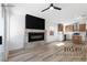 Open-concept living room with fireplace and wood-look tile flooring, and a peek into the kitchen at 10540 Beachwalk Pl, Las Vegas, NV 89144