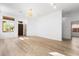 Open living room with wood-look flooring, modern chandelier, and front door view at 10540 Beachwalk Pl, Las Vegas, NV 89144