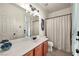 Bright bathroom with a large mirror, white vanity, and shower with a patterned curtain at 11908 Menchaca Ln, Las Vegas, NV 89138
