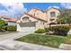 Desirable two-story home with a tile roof, lush front lawn, and a gated entry leading to the front door at 1825 Derbyshire Dr, Las Vegas, NV 89117