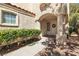 Inviting covered front entrance with a wreath on the door, lush landscaping, and shade trees at 1825 Derbyshire Dr, Las Vegas, NV 89117