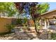 Landscaped backyard features a covered patio, mature trees, a playset, and perimeter block wall at 189 Regal Sunset Ave, Henderson, NV 89002