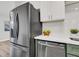 Contemporary kitchen featuring stainless steel refrigerator, quartz counters and white and green cabinets at 2559 Winterwood Blvd, Las Vegas, NV 89142