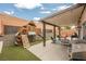 Backyard featuring a covered patio, playground, artificial grass, and brick wall at 2860 Galena Peak Ln, Las Vegas, NV 89156