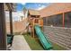 Backyard features a wood playset with slide and ladder on artificial turf at 2860 Galena Peak Ln, Las Vegas, NV 89156