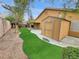 Private backyard featuring an artificial lawn, storage shed, covered patio, and desert landscaping at 310 Sorrelwood St, Henderson, NV 89014