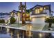 Beautiful home at dusk features a well-lit three-car garage and meticulously landscaped front yard with palm trees at 386 Wiseton Ave, Las Vegas, NV 89183